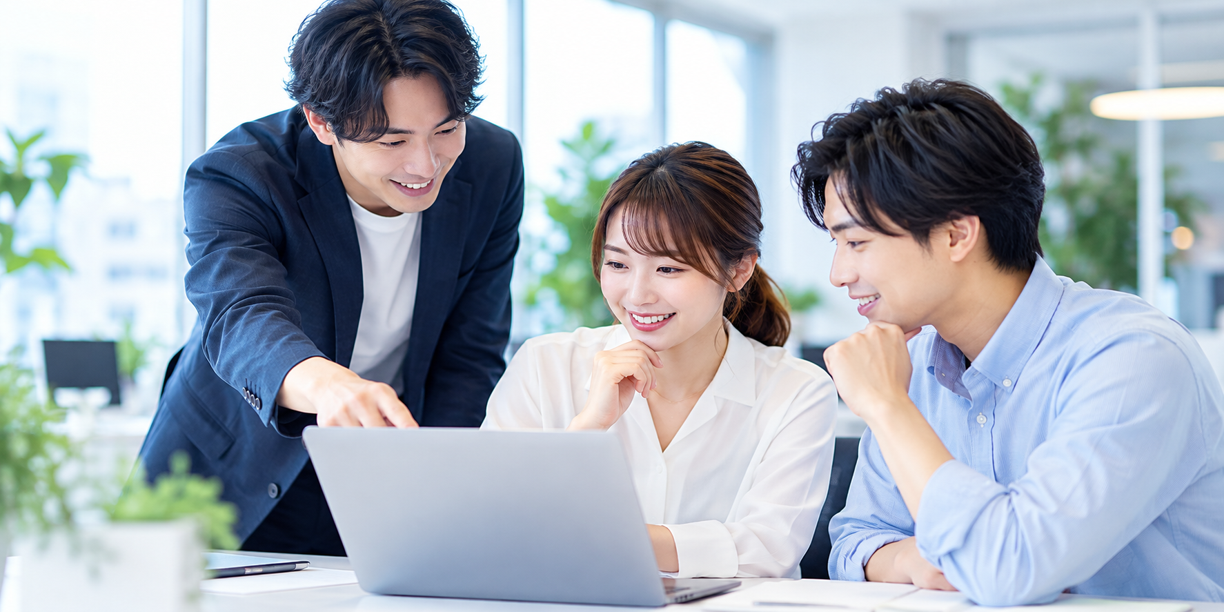 パソコンを囲みながらアプリ事業について相談するスタッフ